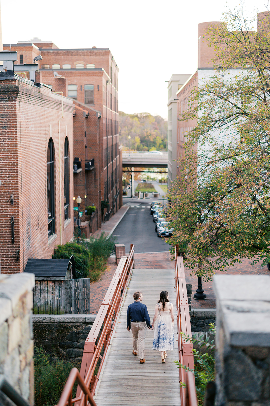 Couple walking across a bridge over the C&O Canal in Georgetown, one of the best engagement photo locations in DC.